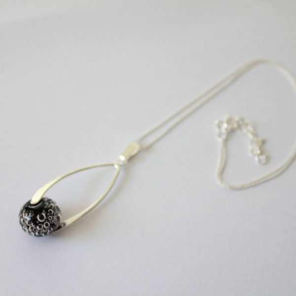 Collier pendentif torsadé avec une perle de verre noire .